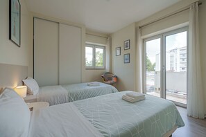 Une chambre d’hôtel avec deux lits, une chaise, une fenêtre et un balcon.