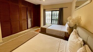 A hotel room with two beds, a ceiling fan, a window with curtains, and a mirror on the wall. - Central Hacienda 5 min from the beach and the famous 5th ave with swimming pool (Playa del Carmen)