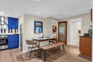 A modern kitchen with blue cabinets, a dining table set for four, and a bench.