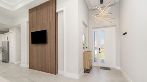 Un intérieur moderne agrémenté d’un mur en bois, d’un téléviseur à écran plat et d’un luminaire contemporain.
