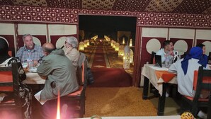 En restaurant med borde og stole, et mønstret loft og udsigt til en pyntet sti.
