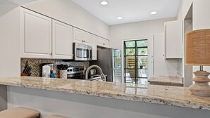 Una cocina moderna con armarios blancos, electrodomésticos de acero inoxidable y encimera de granito.