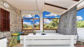 A white table with a wine bottle and glasses, set against a stone wall with a window overlooking greenery. - Charming Home With Pool in Barbariga (Vodnjan)
