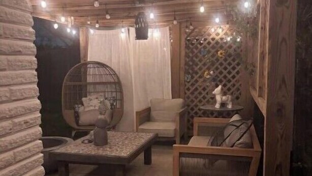 A rustic interior with exposed wooden beams, a stone wall, a round wooden chair, a cushioned bench, and a small table with a decorative item. - Luxury private apartment (Metairie)