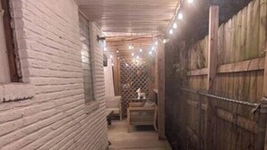 A narrow, enclosed outdoor corridor with a concrete floor, brick walls, and a wooden fence on one side. - Luxury private apartment (Metairie)