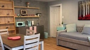 A dining area with a wooden table and chairs, a microwave, and a cabinet. There is a gray sofa and a painting on the wall. - Luxury private apartment (Metairie)