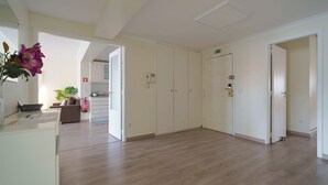 A spacious room with a wooden floor, white walls, and a door with an emergency exit sign.