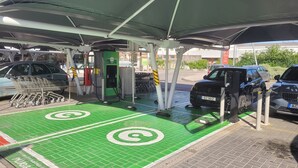A parking area with electric vehicle charging stations, a covered shelter, and a green area marked for electric vehicle charging.