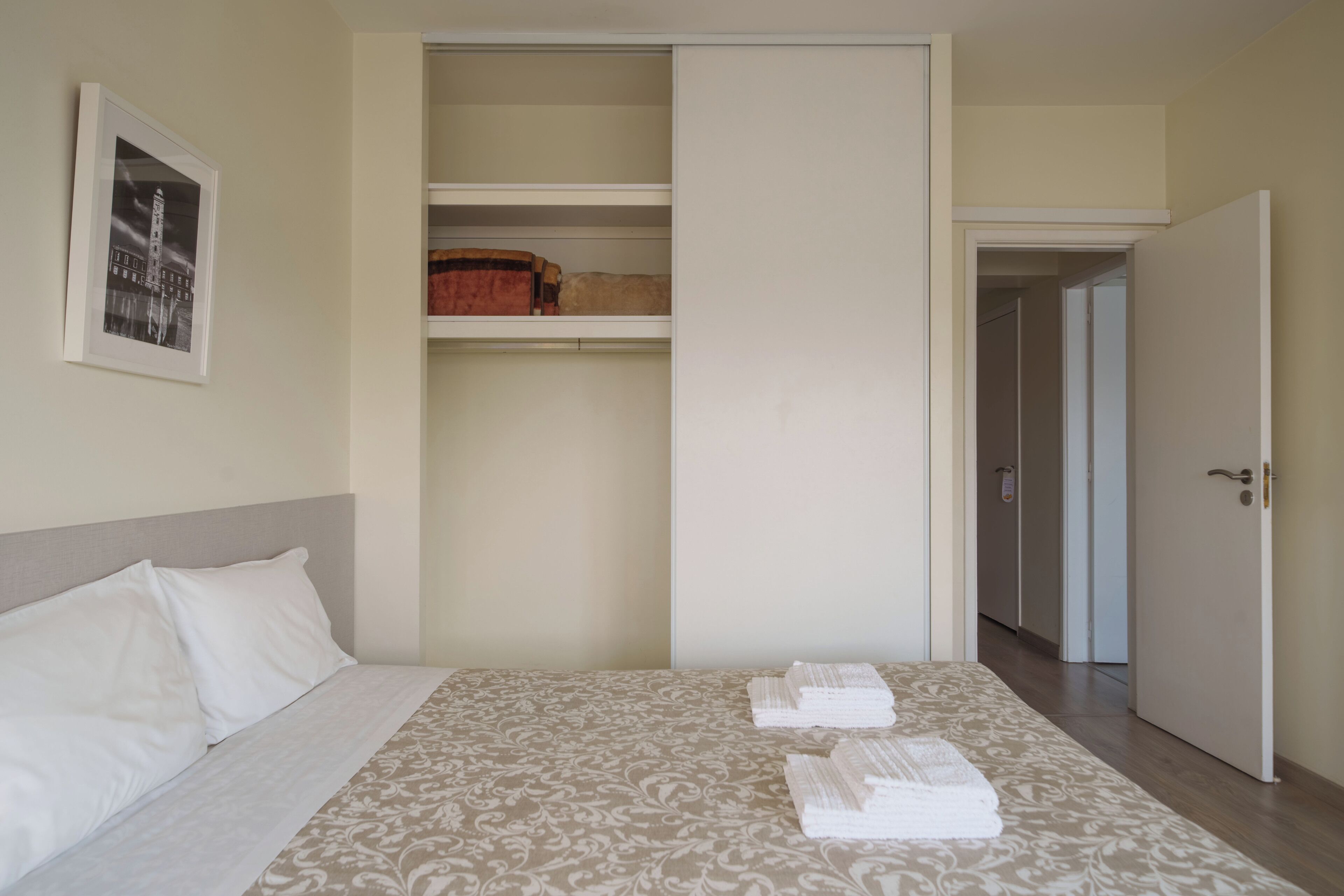 Una habitación de hotel con una cama, un armario y una puerta que da a otra habitación.
