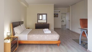 A hotel room with a bed, bedside tables, a dresser, a chair, and a desk with wheels.