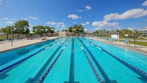 A swimming pool with multiple lanes, surrounded by lounge chairs and palm trees. - Cozy & Peaceful Lido Beach Condo — Steps to the Beach and St. Armands.  (Sarasota)