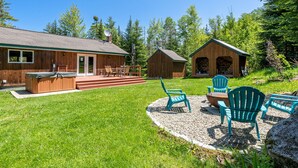 A wooden cabin with a deck, outdoor seating, and a hot tub. - Cozy 3-bedroom cabin in charming Haverhill with Hot Tub, Play Area & Fire Pit (Haverhill)