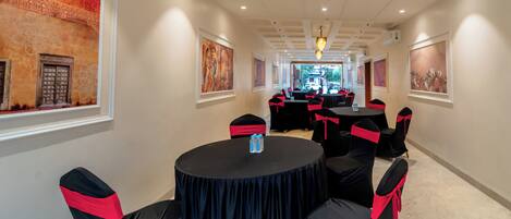 A conference room with round tables and chairs, framed artwork on the walls, and a chandelier.