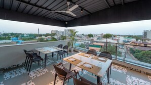 Terraza en la azotea con mobiliario para comer, incluyendo mesas y sillas, y vistas a la ciudad.
