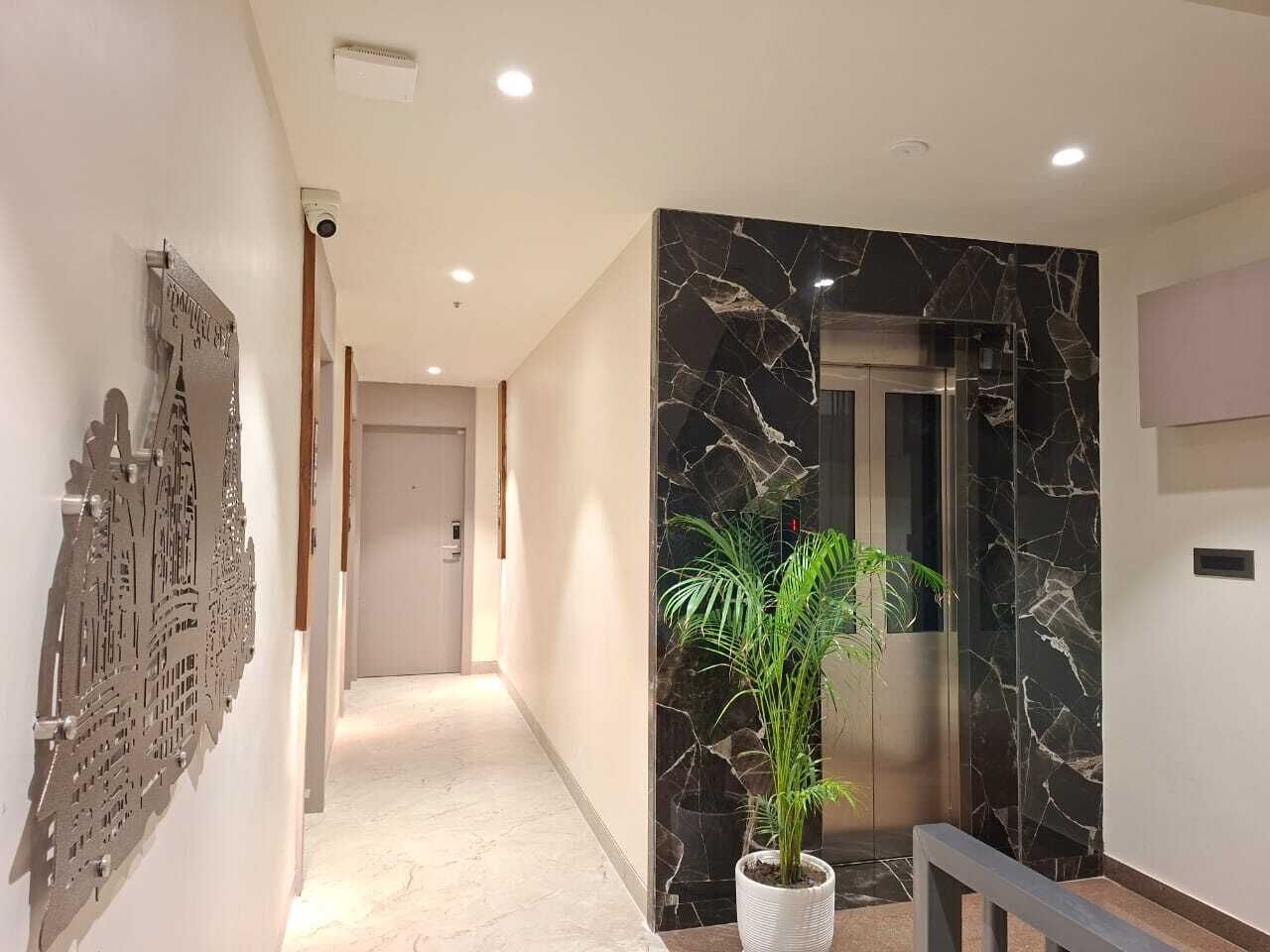 A modern hallway with a marble wall, a potted plant, and a door leading to a room.