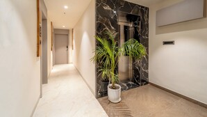 Un pasillo moderno con suelo de mármol, una planta en maceta y una pared de mármol.
