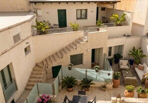 Une cour intérieure à plusieurs niveaux, dotée d’un espace extérieur aménagé avec des sièges, des plantes en pot et un escalier.