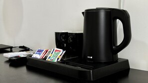 A black coffee maker with a tray, a remote control, and a few packets on a black tray. - B&B Alla Stazione (Palermo)