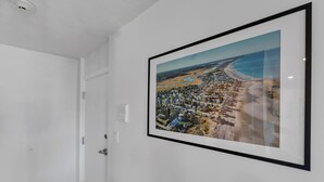 A hallway with a framed aerial photograph of a coastal town on the wall.