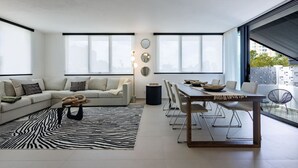 A modern living room with a sectional sofa, a dining table with chairs, a zebra-patterned rug, and large windows with city views. - Modern & Spacious Retreat in Hato Rey | Unit 2 (San Juan)