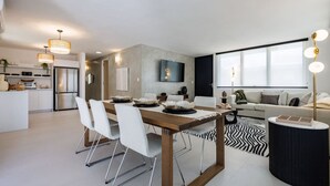 A modern living room with a dining area, a kitchen, and a large window. - Modern & Spacious Retreat in Hato Rey | Unit 2 (San Juan)
