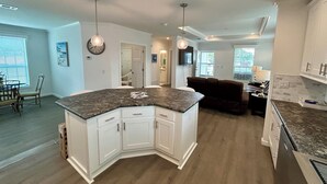 A modern kitchen with white cabinets, a granite countertop, and pendant lighting. - Oak Hill Waterfront Retreat – Unplug, Unwind, and Enjoy the Sunset (Oak Hill)