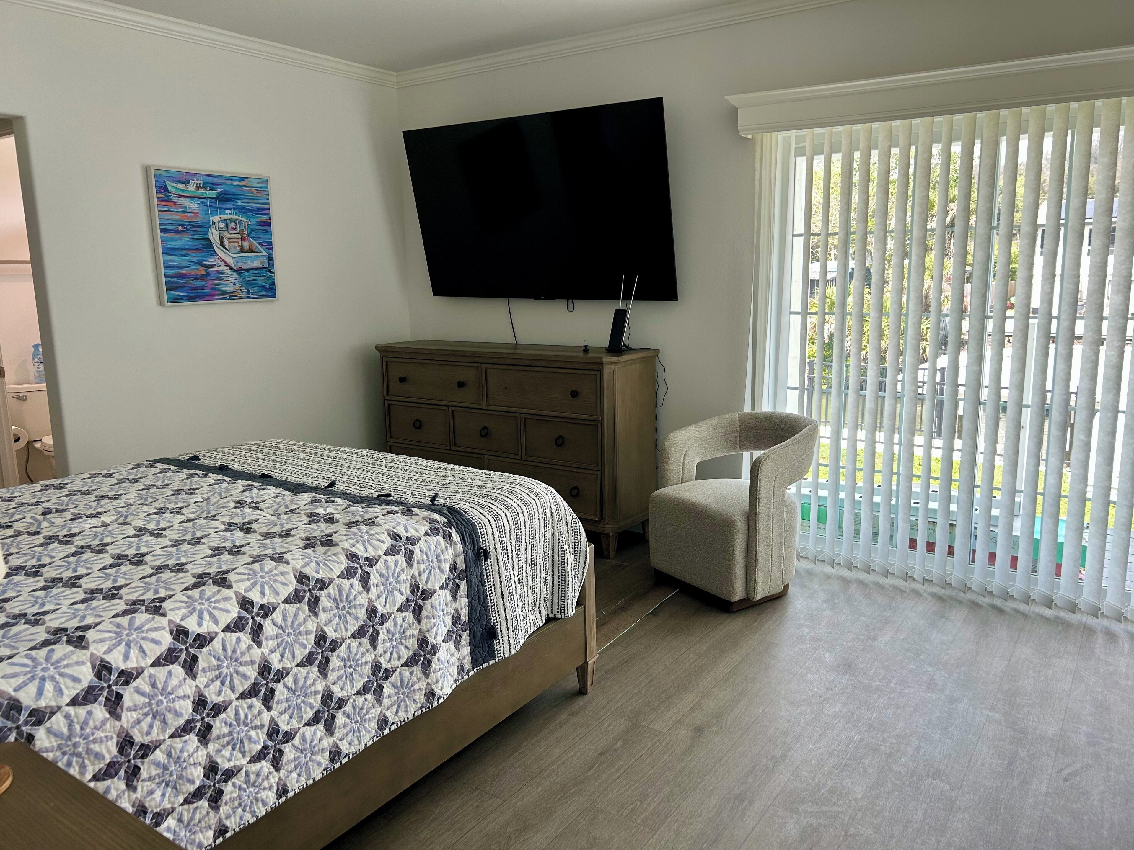 Une chambre à coucher avec un lit, une commode, un téléviseur et une chaise.
