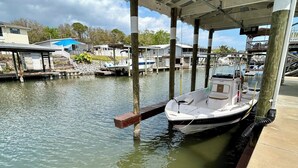 A docked boat at a marina with a covered structure, calm water, and a clear sky. - Oak Hill Waterfront Retreat – Unplug, Unwind, and Enjoy the Sunset (Oak Hill)