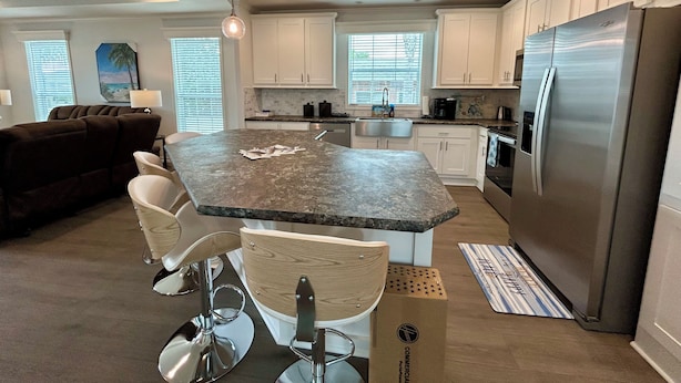A modern kitchen with white cabinets, a large island, stainless steel appliances, and pendant lighting. - Oak Hill Waterfront Retreat – Unplug, Unwind, and Enjoy the Sunset (Oak Hill)