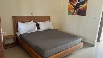 A modern bedroom with a wooden bed frame, grey bedding, and a colorful abstract painting on the wall.