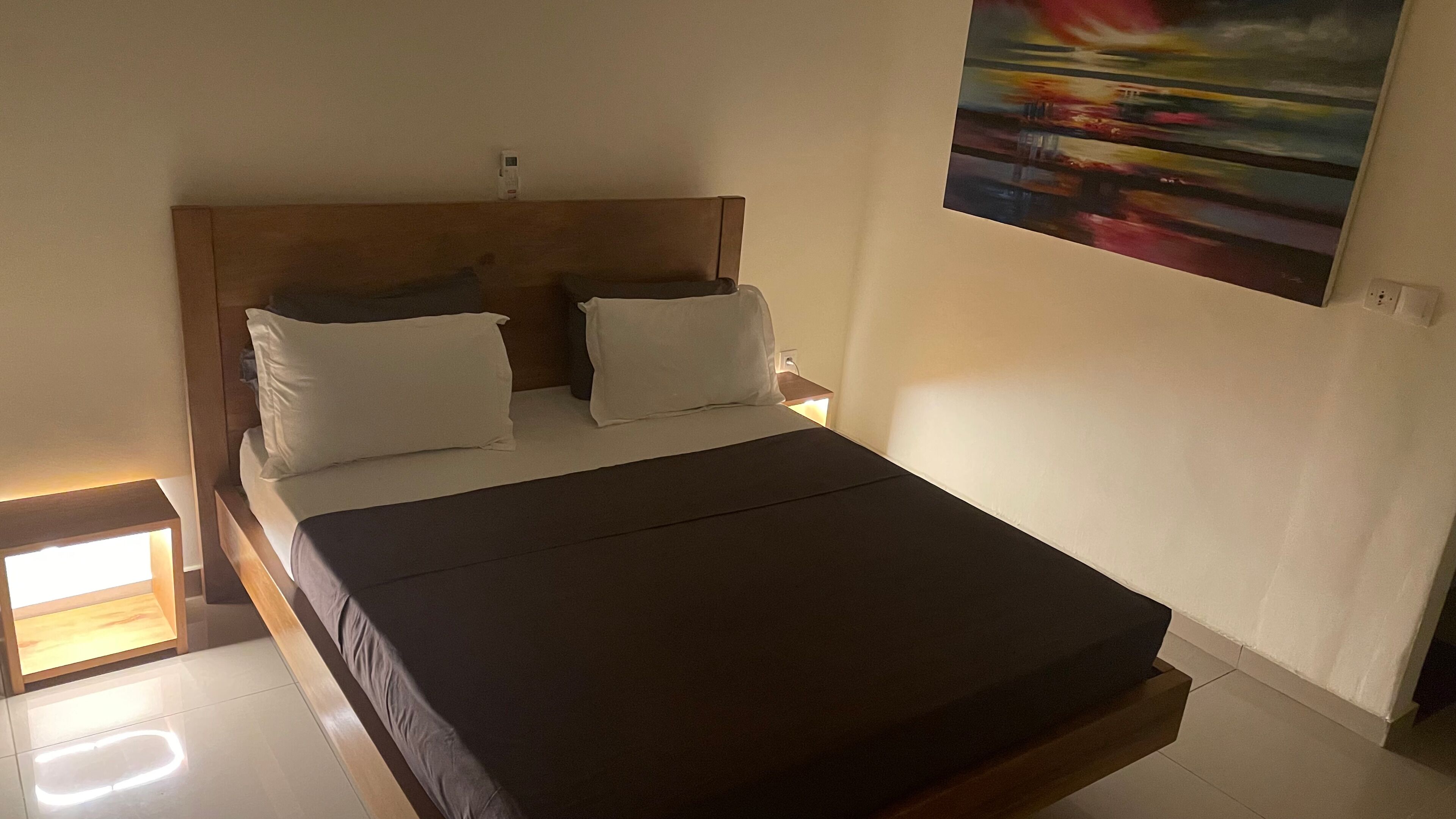 Una cama con cabecera de madera, dos almohadas blancas y un colchón oscuro.
