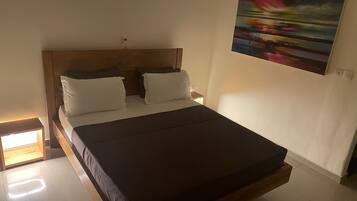 A bed with a wooden headboard, two white pillows, and a dark mattress.