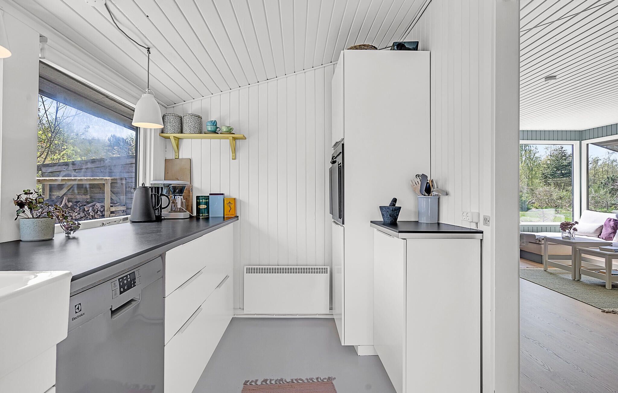 Une cuisine moderne avec des meubles blancs, un plan de travail noir et une fenêtre donnant sur un jardin.