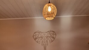 A bedroom with a large bed, wooden ceiling, and a geometric wall art piece.