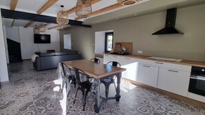 A modern kitchen with a dining area, a sofa, and a TV.