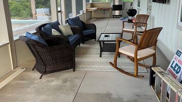 Une terrasse couverte, aménagée avec des meubles en osier, une table et des chaises.