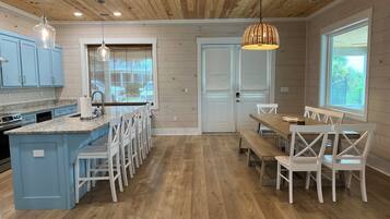 Une cuisine moderne avec un îlot central bleu, des chaises blanches et une table à manger en bois.