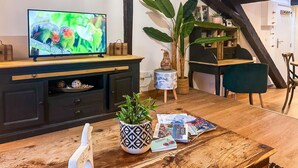 A cozy living room with a television, a wooden table with magazines, a potted plant, and a bookshelf. - Casa Jungle loft rue du Paquier (Annecy)