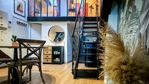 A modern interior with a wooden floor, a dining area with a table and chairs, a staircase, and a decorative plant. - Casa Jungle loft rue du Paquier (Annecy)