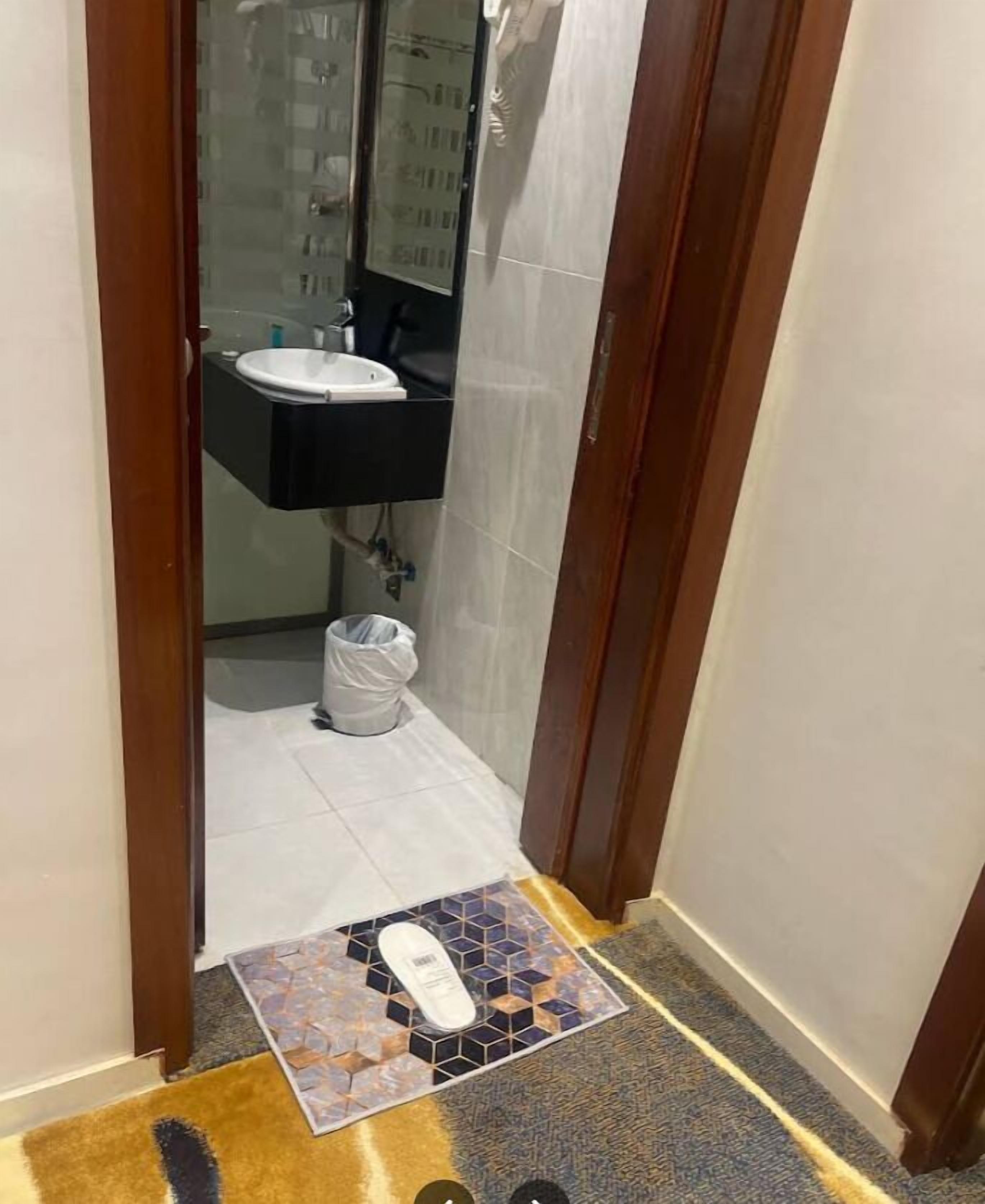 Ein schmaler Flur, der zu einem Badezimmer mit einem weißen Waschbecken und einer Dusche führt.