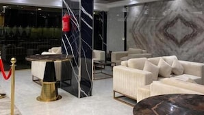 A modern lobby with a marble floor, a large sofa, a round table, and a decorative column. - Zekra Alkawther Hotel (Taif)
