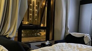 A hotel room with a large window, curtains, a bed, and a nightstand. - Zekra Alkawther Hotel (Taif)