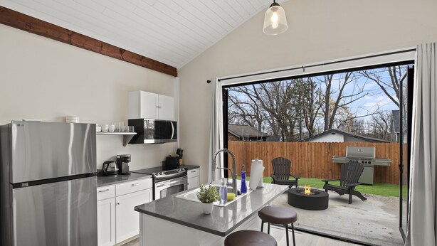 A modern kitchen with a stainless steel refrigerator, white cabinets, and a large island with stools.