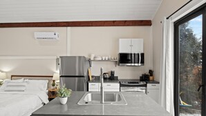 A modern kitchen with a central island, stainless steel appliances, and a view of the outdoors.