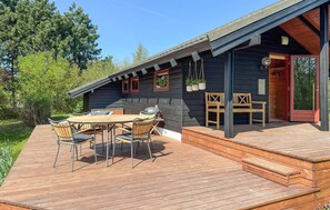 A wooden deck with a round table and chairs, a grill, and a wooden bench. - 2 bedroom amazing home in Præstø (Præstø)