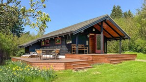 Une cabane dotée d’une terrasse, de meubles de jardin et d’un porche abrité.