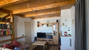 Una sala de estar acogedora con techo de madera, un sofá, una mesita de centro y una estantería llena de libros.