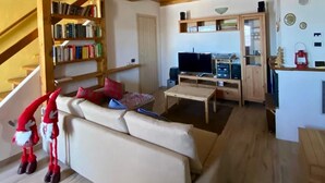 Una sala de estar acogedora con techo de madera, un sofá, una mesa de centro y una estantería.