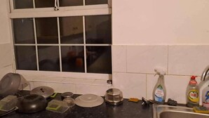 Una cucina con una finestra, diversi utensili da cucina e prodotti per la pulizia.