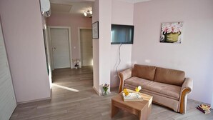 A living room with a beige sofa, a wooden coffee table, and a flat-screen TV mounted on the wall. - Lovely apartment in Pula (Pula)